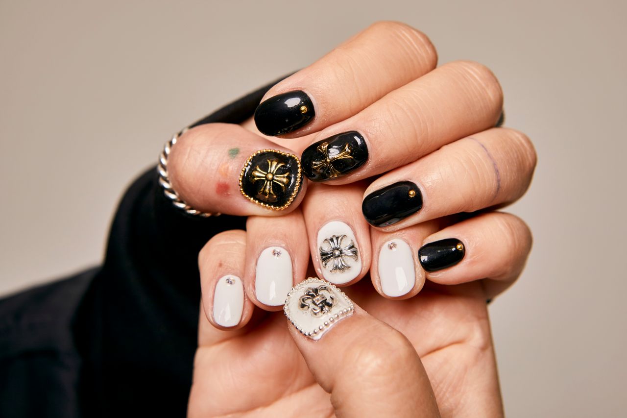 pexels photo 18730147 Close-up of women's hands showcasing artistic black and white nail art with ornate embellishments.